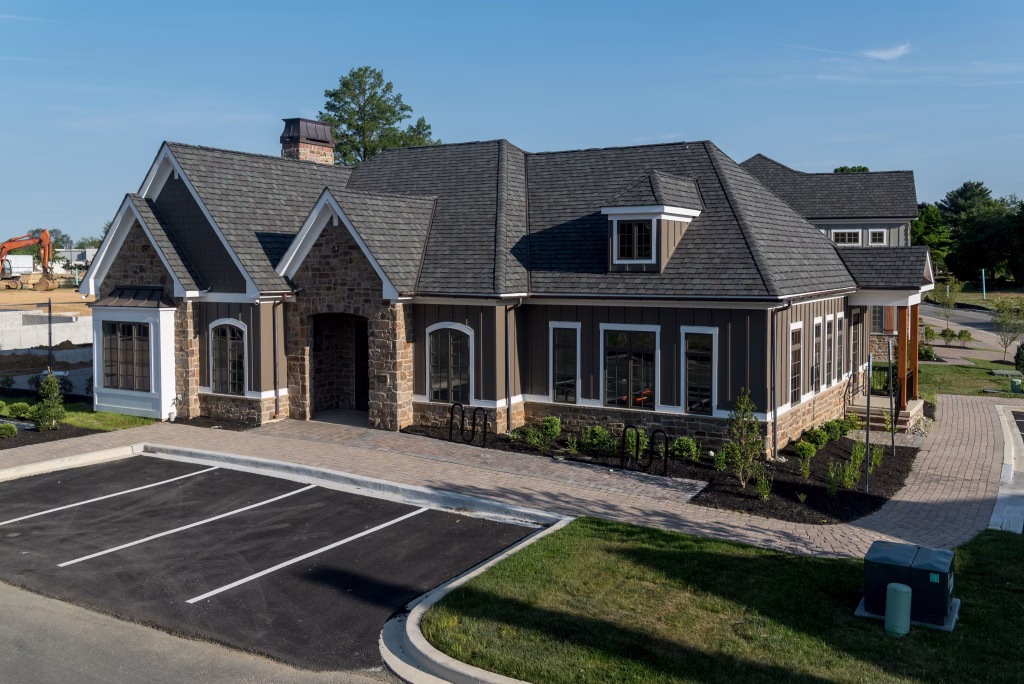 Craftsman commercial building with stone facade beside a paved parking lot in a suburban area.