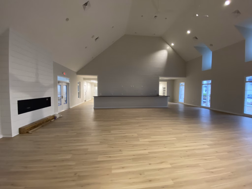 Modern commercial clubhouse interior design with a fireplace and wood floors by Wade Architecture