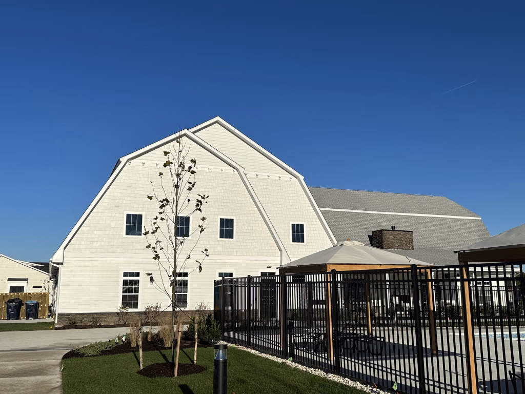 Modern commercial clubhouse exterior design featuring a swimming pool and metal fencing by Wade Architecture.