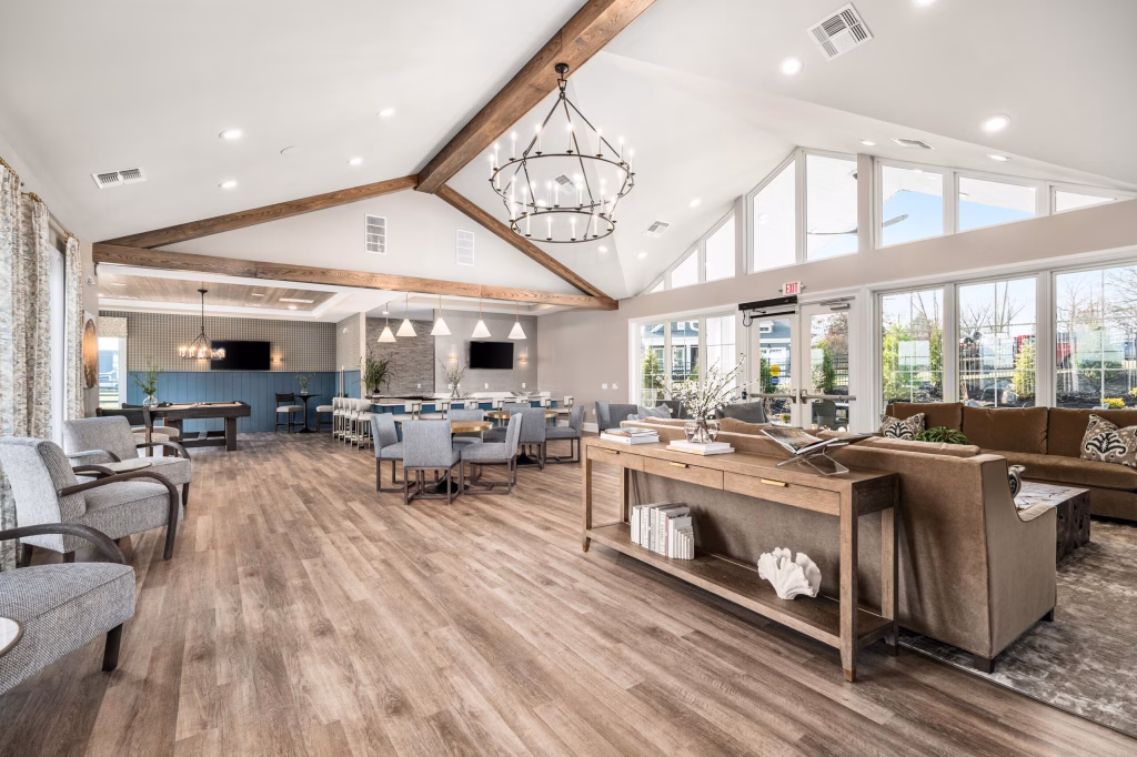 Modern commercial clubhouse interior design with a bar, pool table, and large windows by Wade Architecture.