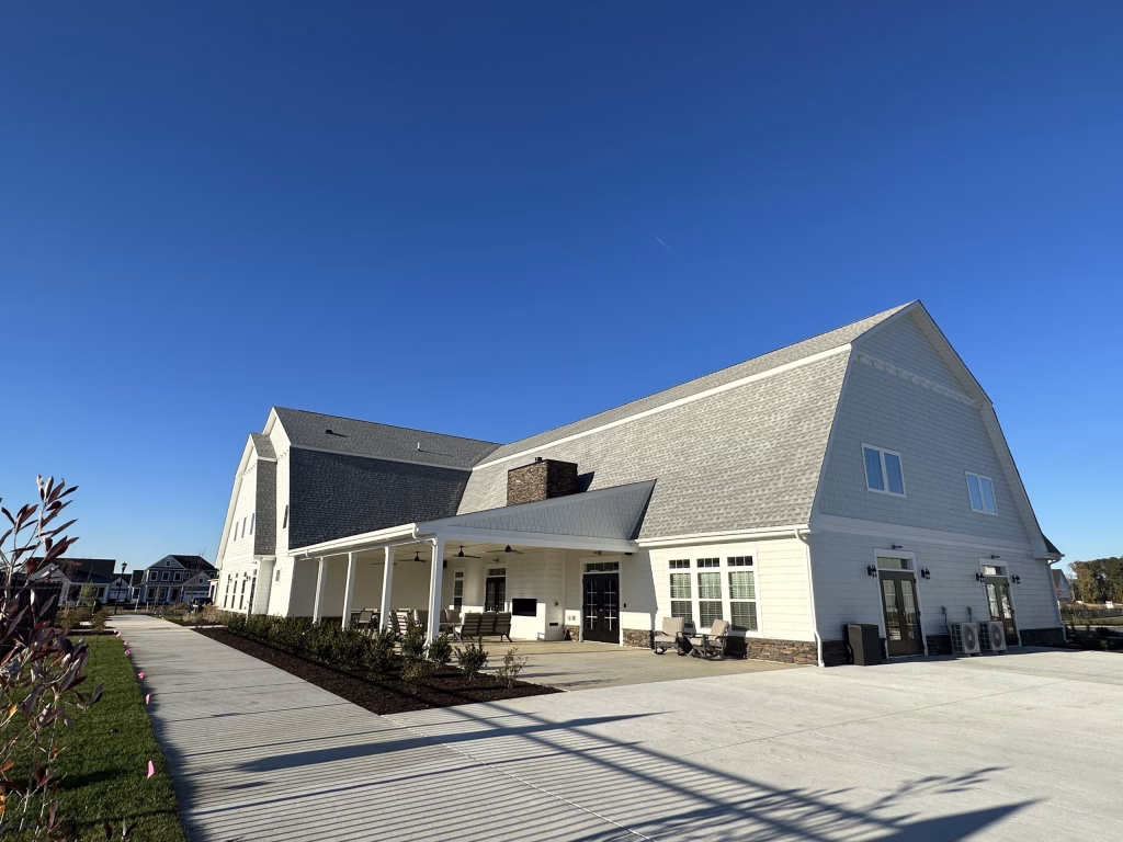 Large modern event space exterior featuring white siding, a covered patio, and stone water table accents.