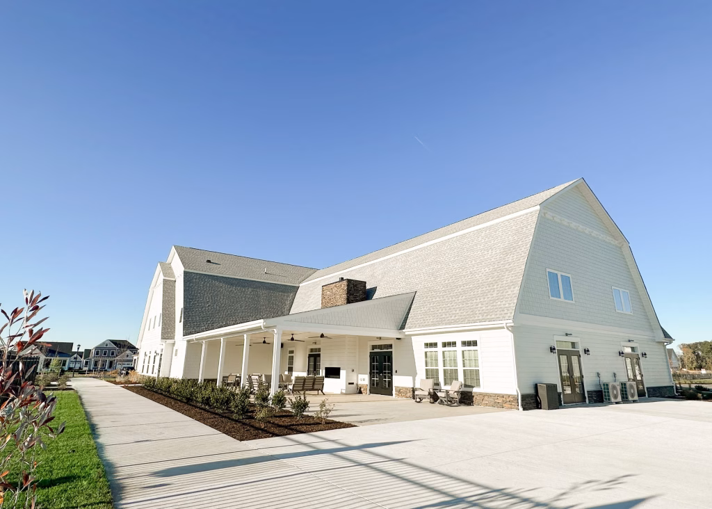 Modern commercial clubhouse exterior featuring a large pitched roof and patio at Towerhill Clubhouse