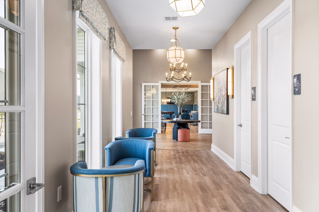 Large modern commercial hallway featuring a bright hallway, blue seating, and wood floors at The Landings Clubhouse.